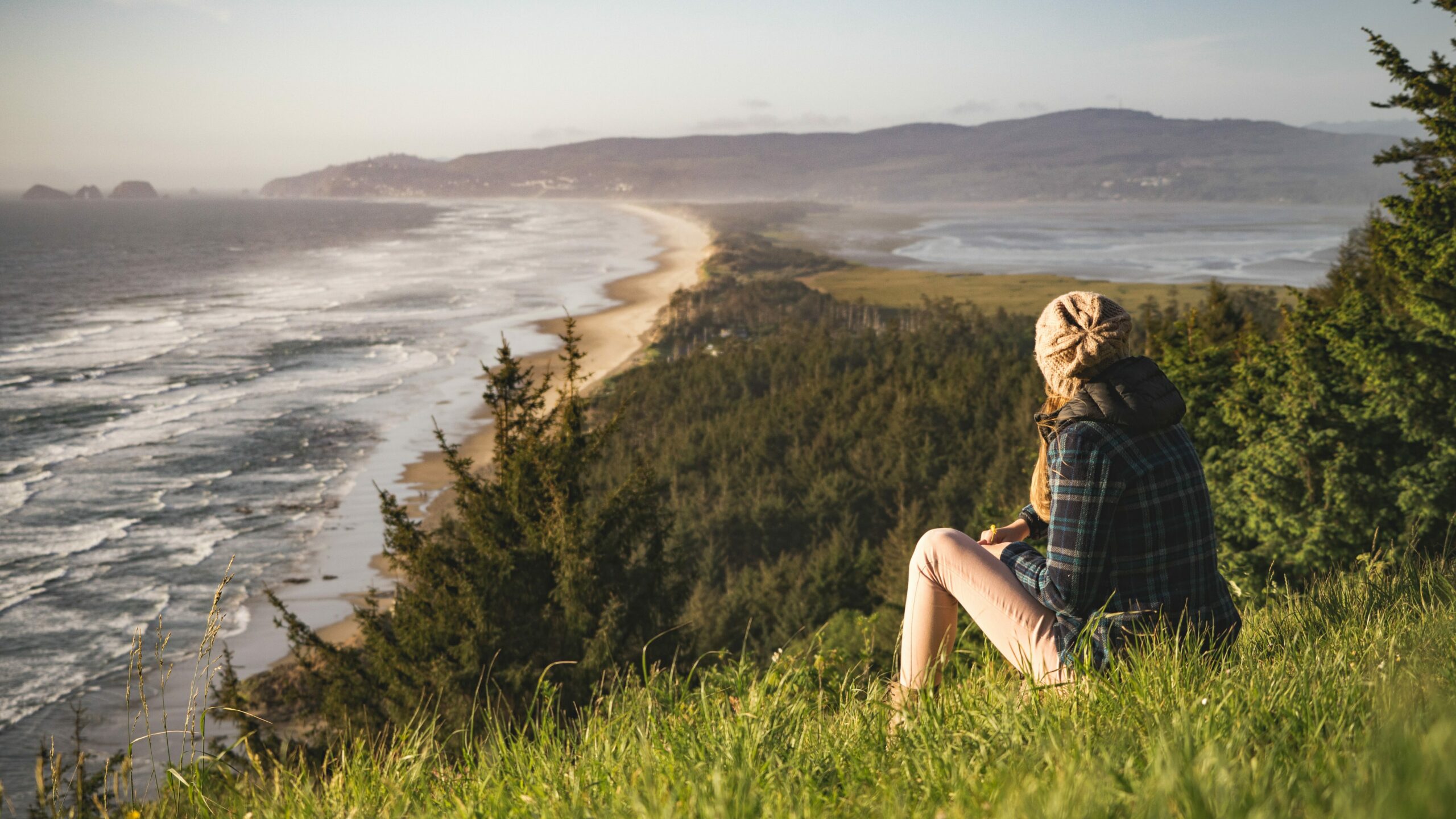 solo travel of a female gazing at a seascape with mountains.